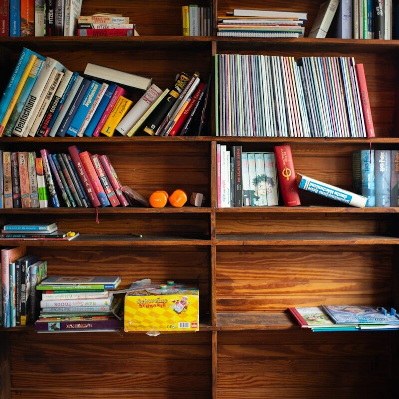 A bookshelf filled with lots of books on top of a wooden floor