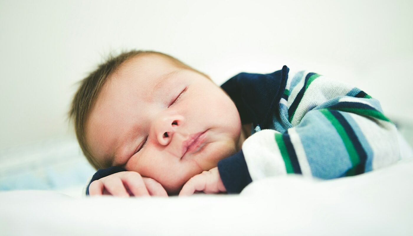baby in black and white stripe shirt lying on bed